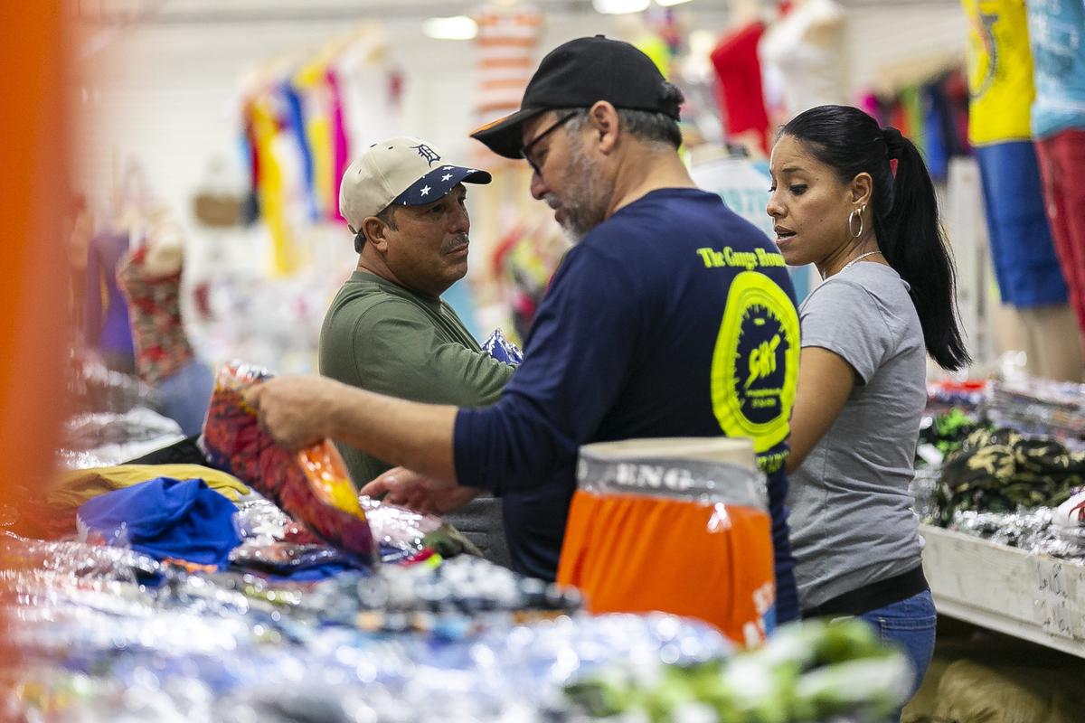 Juan Cantu (izq.) y Alejandro Dgyves son atendidos por la empleada Perla Díaz, en Konga Store, en una zona de almacenes y tiendas en Miami Lakes popular por los precios bajos.
