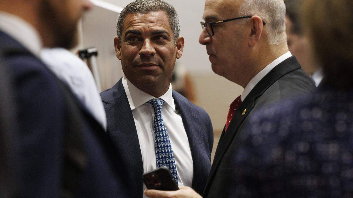 Miami Mayor Francis Suarez, center, with Emilio Gonzalez, right, the mayoral candidate who filed the lawsuit against Miami, chat before a  hearing at the Third District Court of Appeal. A judge ruled changing the election date requires voter approval.