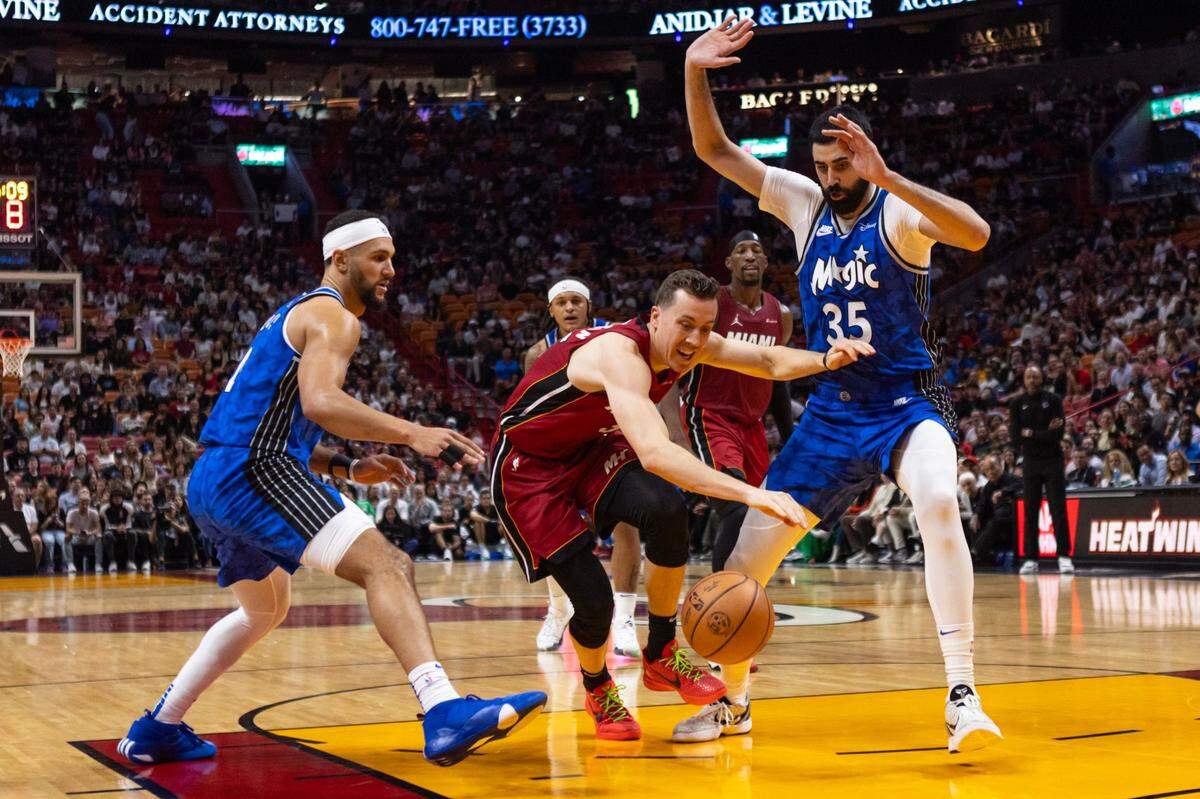 El jugador del Heat Duncan Robinson (55) trata de pasar la marca de Jalen Suggs (izq.) y Goga Bitadze, del Magic de Orlando, en el partido celebrado el 12 de enero de 2024 en Miami.