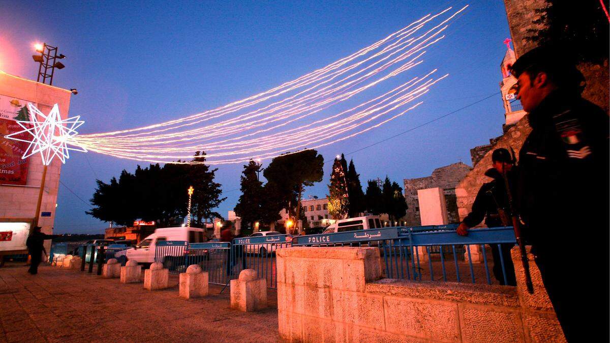 Policías palestinos bajo una estrella que decora Manger Square, en la ciudad cisjordana de Belén, durante las fechas navideñas. Al fondo, la iglesia de la Natividad, el lugar aceptado tradicionalmente como el del nacimiento de Jesús.