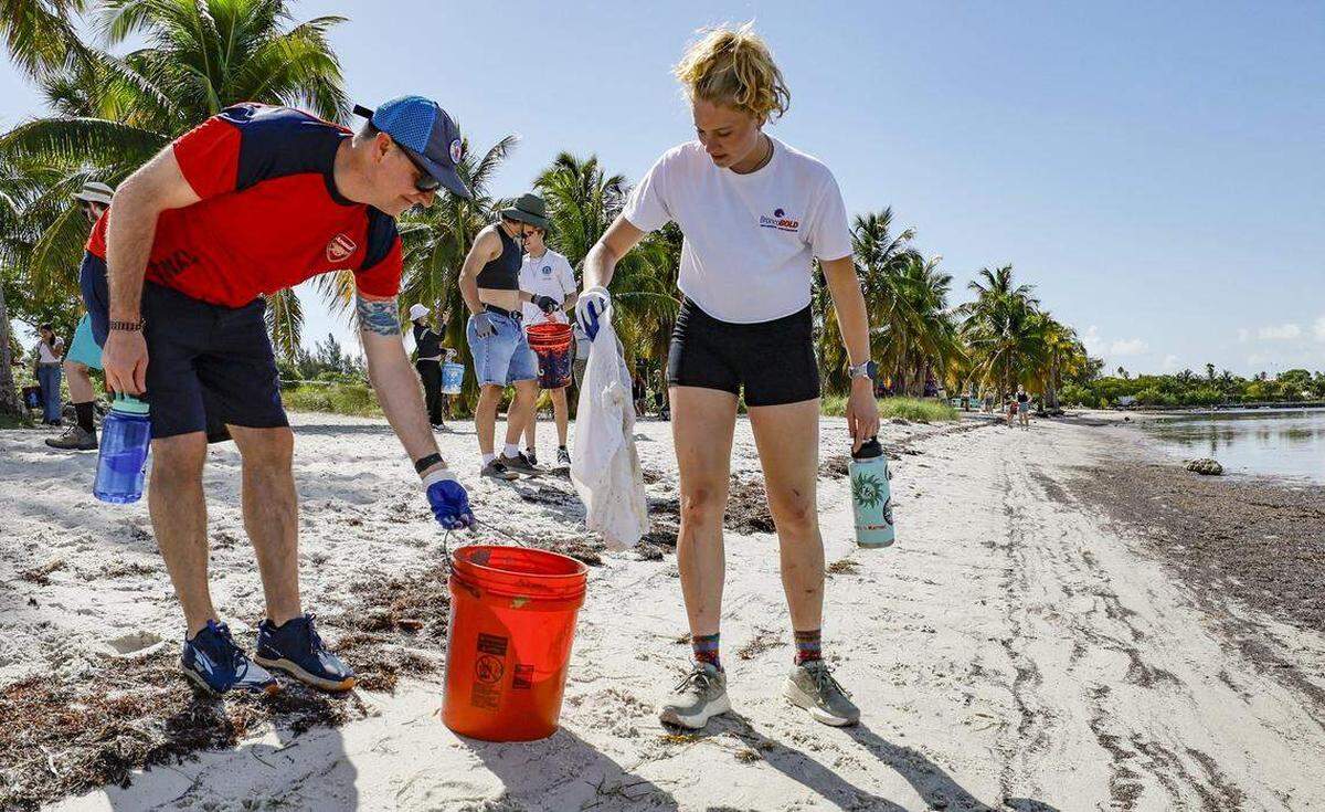 Ethan Sims se une a su hija Zoe Sims, de 17 años, de Boise, Idaho, durante una limpieza de playa en la Calzada Rickenbacker el viernes. Ella estaba allí para asistir a una importante conferencia sobre el clima para jóvenes celebrada en la Universidad de Miami.
