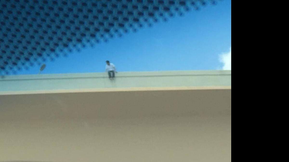 En esta imagen enviada por un lector, un hombre se sienta en el borde del elevado de la autopista Dolphin. Las autoridades dijeron que los negociadores eran capaces de hablar del hombre menos. 