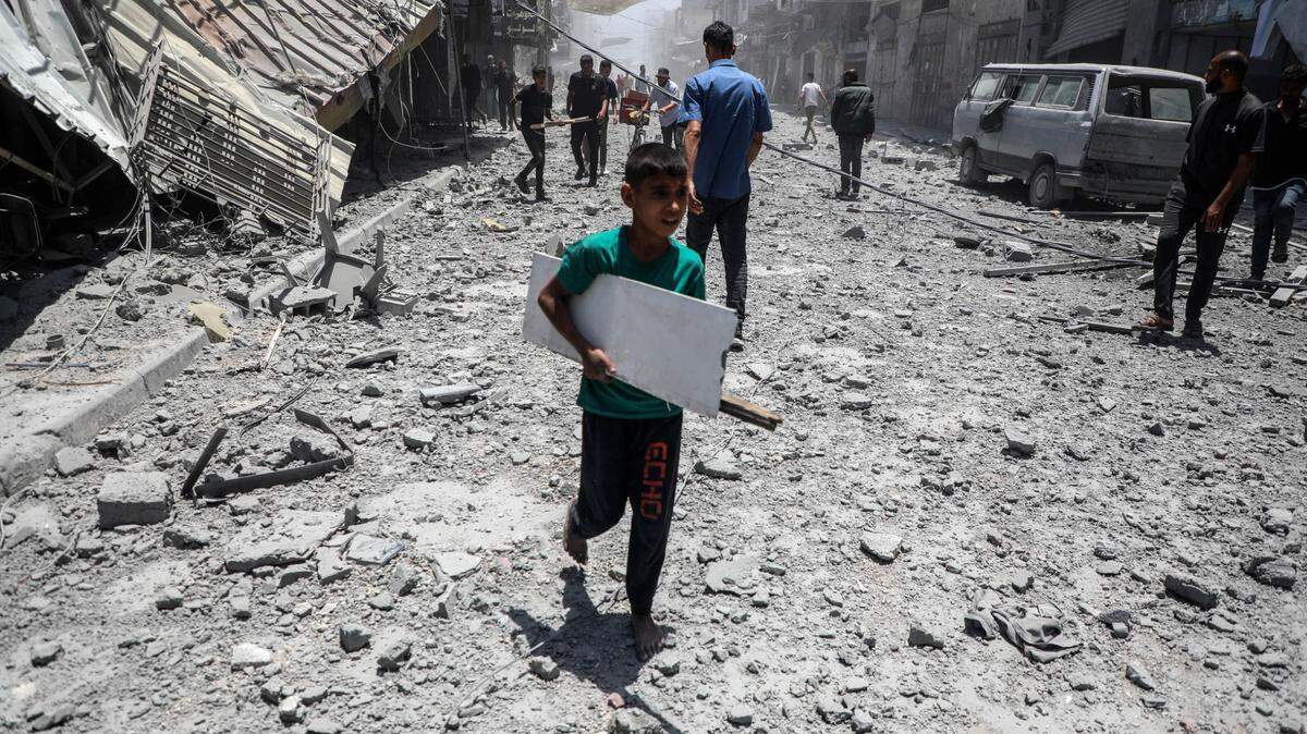 Varios palestinos caminan entre los escombros de las casas destruidas después de un ataque aéreo israelí en la ciudad de Gaza, el domingo, 31 de mayo de 2025.