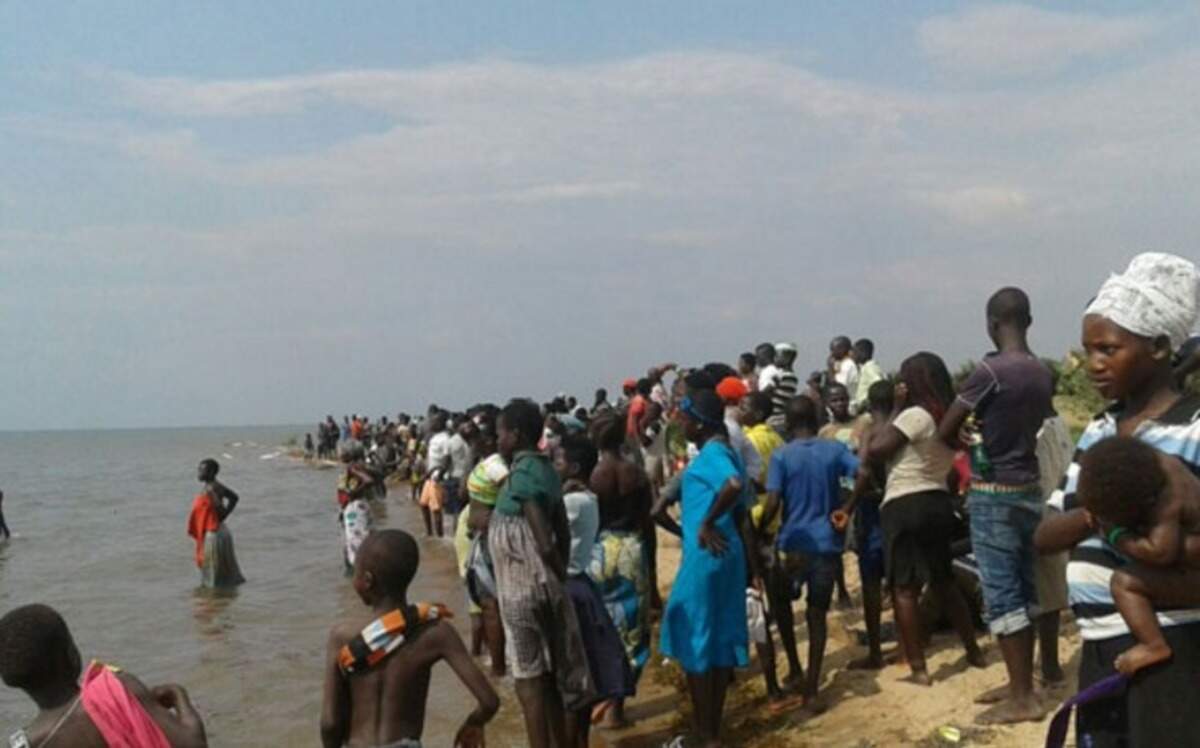 Residentes de un pueblo de Uganda observan las labores de rescate en el Lago Alberto, donde al menos nueve personas murieron y otras 21 permanecen desaparecidas al volcarse el domingo el barco en el que viajaba un equipo de fútbol y sus seguidores.