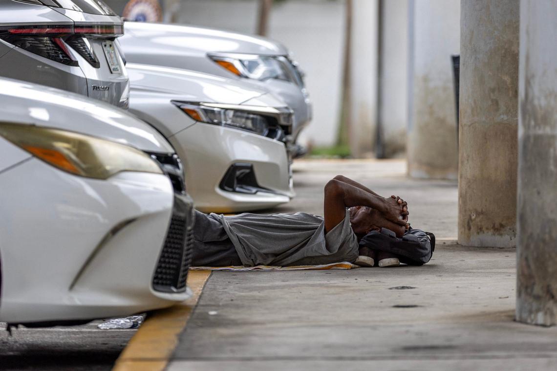A man sleeps inside a parking lot underneath the expressway while waiting for the nonprofit One World One Heart to deliver free meals to the homeless population on Thursday, Sept. 12, 2024, in Miami.