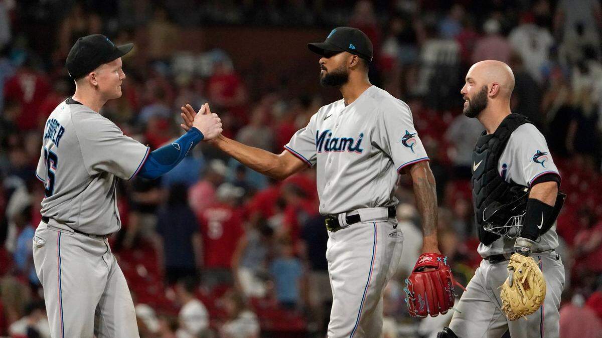 El derecho de los Marlins Sandy Alcántara (centro) es felicitado por el receptor Jacob Stallings y Garrett Cooper (izq.) tras el triunfo 4-3 ante los Cardenales, el 29 de junio de 2022 en San Luis.