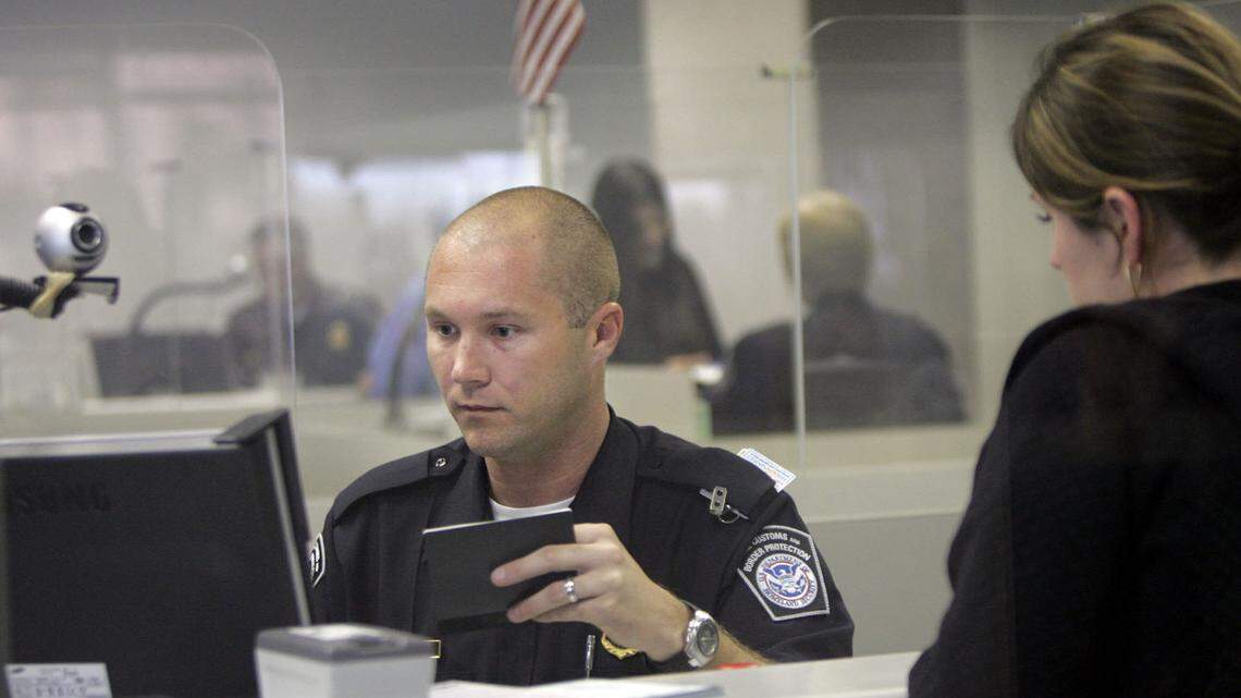 An immigration agent verifies a woman’s passport.