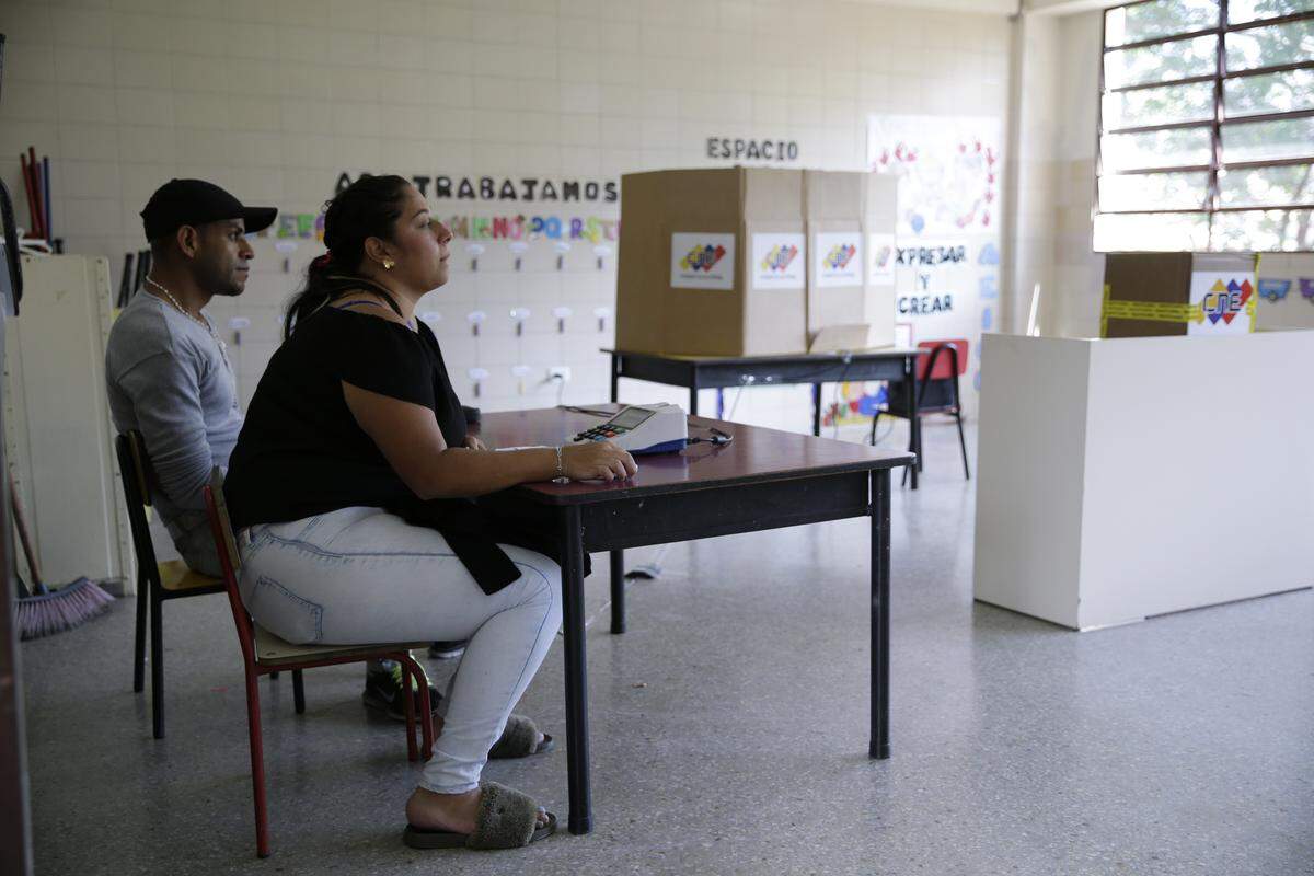 Trabajadores de un centro electoral en Caracas esperan por votantes el 20 de mayo del 2018.