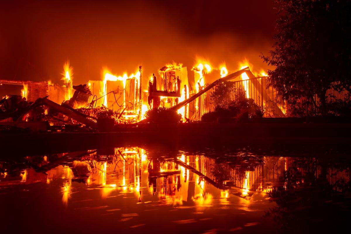 Una casa en llamas se refleja en una piscina durante el incendio en California, el 27 de julio de 2018. Dos bomberos murieron durante el siniestro.