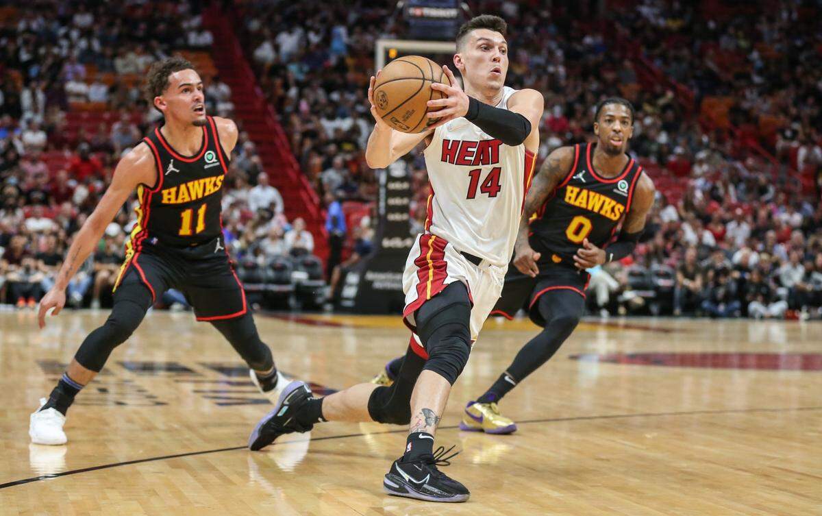 El escolta del Heat Tyler Herro (centro) entra al aro ante la marca de Trae Young (izq.) y Delon Wright, de los Hawks de Atlanta, en el partido celebrado el 8 de abril de 2022 en Miami.