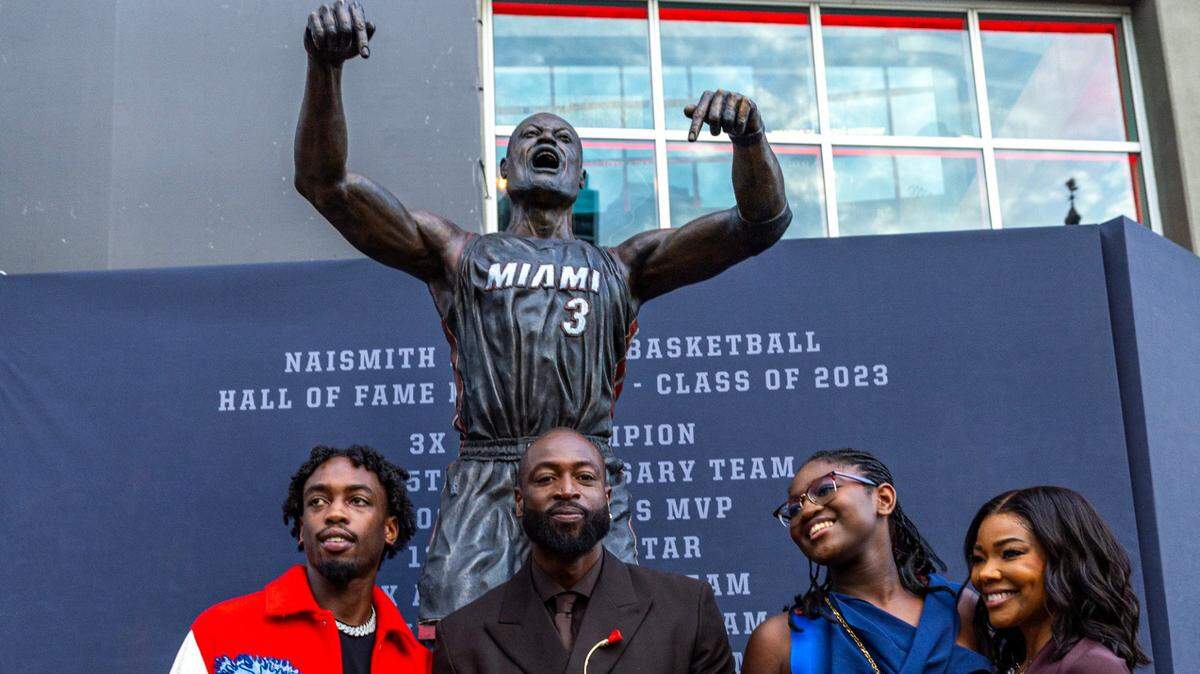 Dwyane Wade posa con su familia el domingo delante de su estatua en la entrada del Kaseya Center, la cancha del Heat en Miami.