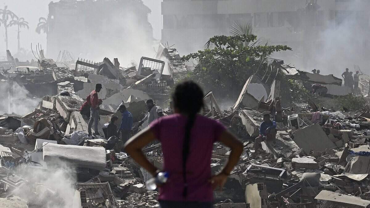 A woman looks at the destruction as people search through the rubble of collapsed buildings following a twin earthquake in Caraballeda, La Guaira State, about 40 km northeast of Caracas, on June 25, 2026. The death toll from twin quakes, measured at magnitudes 7.2 and 7.5, has risen to at least 188, with more than 1,520 others injured, top lawmaker Jorge Rodriguez reported, while residents continue searching for missing relatives. (Photo by Federico PARRA / AFP via Getty Images)