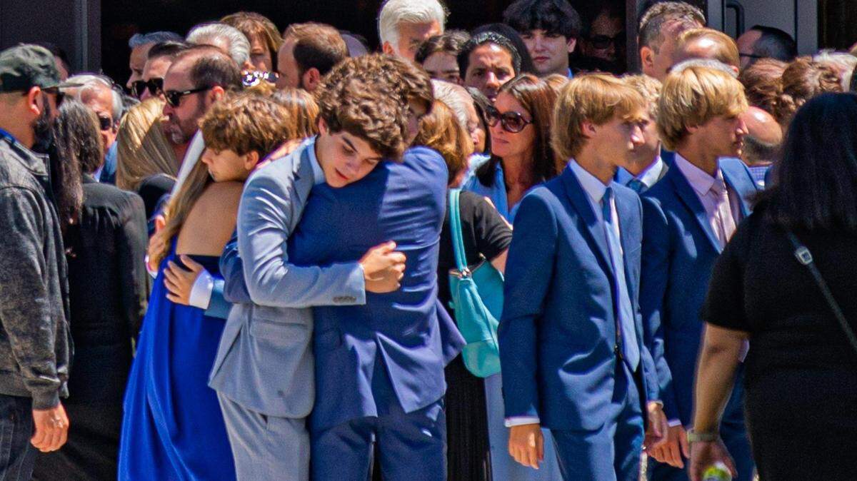 Personas se abrazan después de la misa de funeral de Lucy Fernández en la Iglesia de la Epifanía en el área de South Miami el lunes 12 de septiembre de 2022.