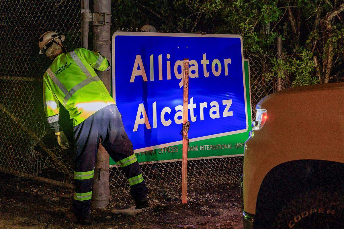 Two workers finish erecting the “Alligator Alcatraz” sign at the entrance of the newly constructed migrant camp in Ochopee, Florida, in the Everglades late Wednesday, July 02, 2025.