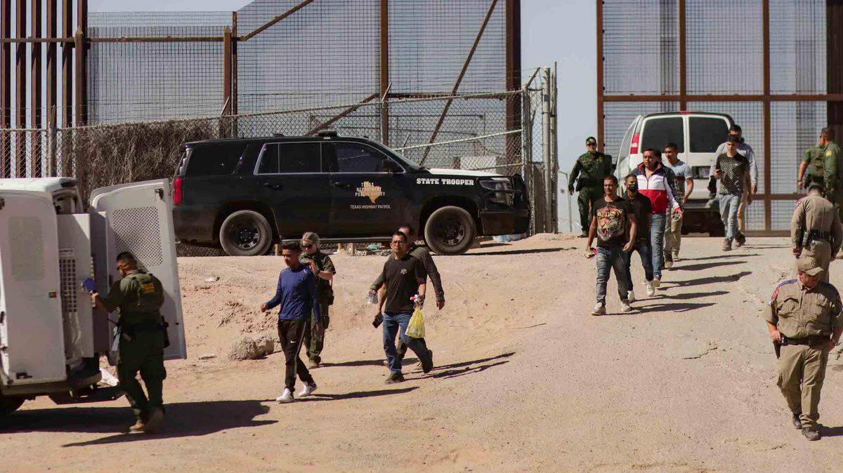Miembros de la Patrulla Fronteriza de Estados Unidos llevan a los migrantes detenidos a un vehículo junto al muro fronterizo en El Paso, Texas, EE.UU., 11 de mayo de 2023.