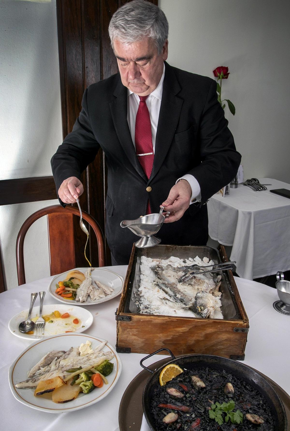 Domingo Gándara, dueño de La Dorada, vierte aceite de oliva en la preparación de la Lubina salvaje del mediterráneo a la sal, que se sirve con vegetales y patatas a lo pobre en el restaurante La Dorada, en Coral Gables, el 19 de diciembre de 2019.