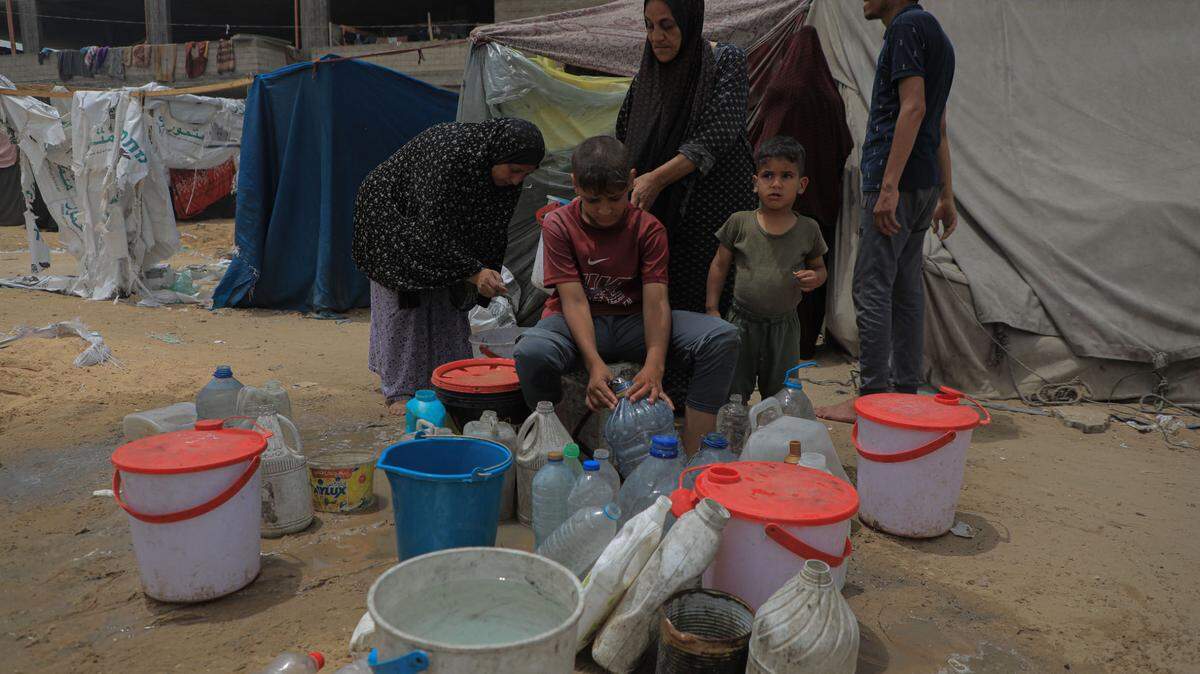 Un grupo de palestinos recogen agua en un campamento temporal de refugiados en la ciudad de Rafah, en el sur de Gaza, el viernes 10 de mayo de 2024. Agencies de Naciones Unidas han alertado sobre la necesidad de que estos campamentos reciban ayuda humanitaria tan pronto sea posible.