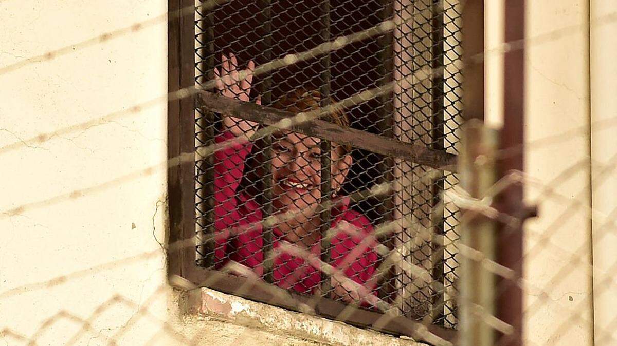 Former Bolivian President Jeanine Anez waves from inside the Miraflores women's prison in La Paz, on November 5, 2025. Bolivia's Supreme Court on Wednesday overturned the 10-year prison sentence handed to former right-wing president Jeanine Anez in 2022 over an alleged plot to oust her predecessor Evo Morales. (Photo by Jorge BERNAL / AFP) (Photo by JORGE BERNAL/AFP via Getty Images)