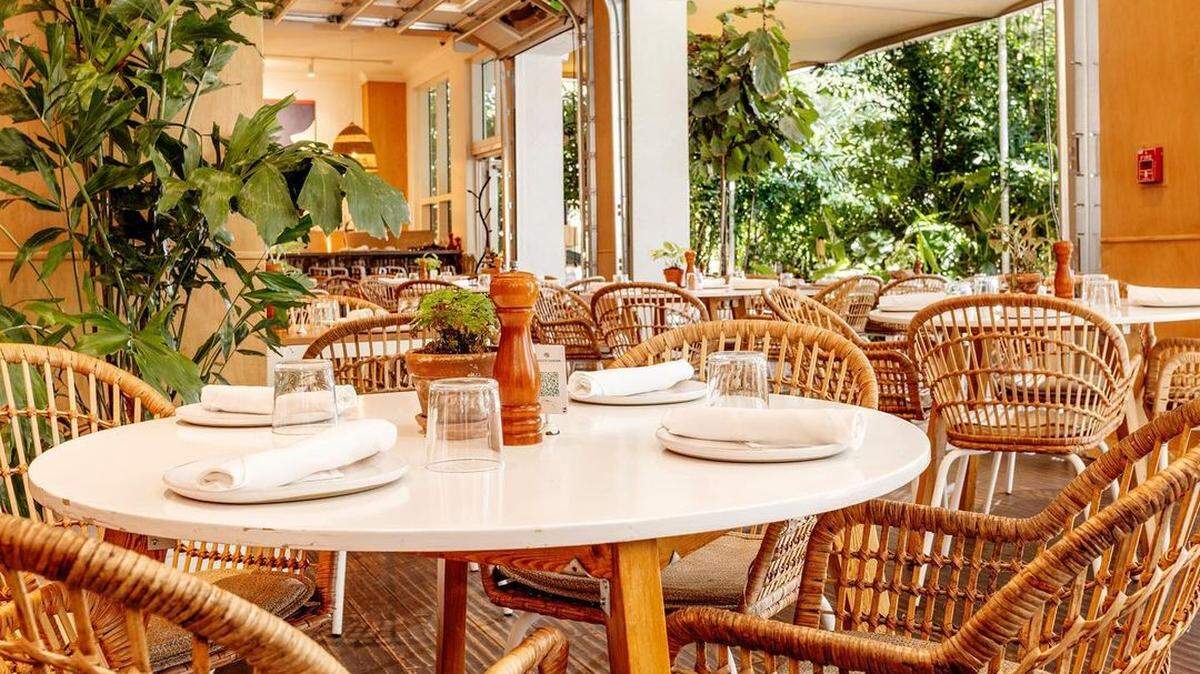 El comedor privado blanco y luminoso de Peacock Garden ofrece una extensión del exuberante jardín tropical del restaurante.