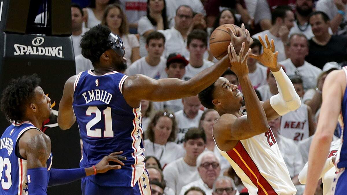 El centro de Filadelfia Joel Embiid (izq.) trata de robarle el balón a Hassan Whiteside, del Heat, en el partido efectuado el 21 de abril de 2018 en Miami.