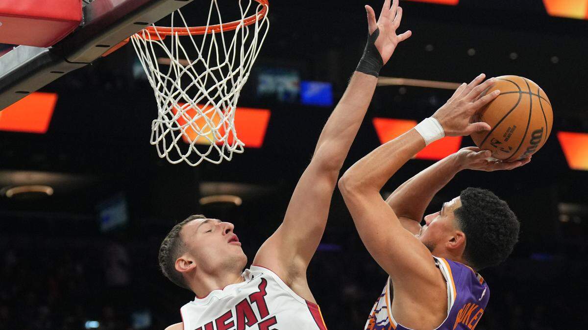 El jugador del Heat Nikola Jovic (izq.) trata de bloquear el tiro de Devin Booker, de los Suns, en el partido celebrado el 6 de noviembre de 2024 en el Footprint Center en Phoenix.
