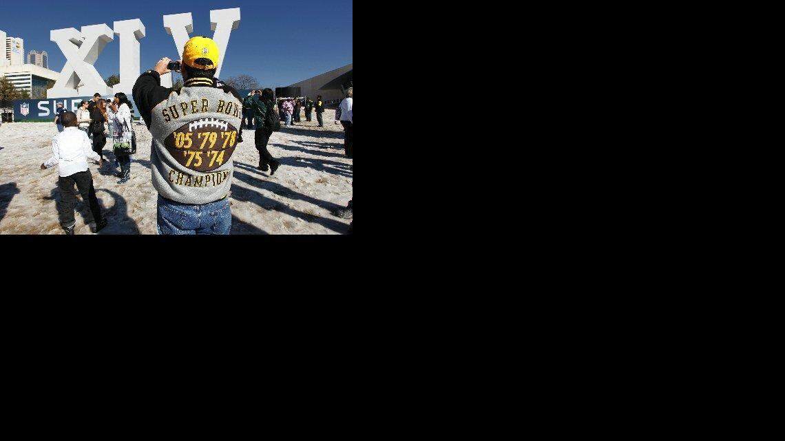 FANATICOS DEL Pittsburgh Steelers se toman una foto frente a la valla del Super Bowl XLV, en el Centro de Convenciones de Dallas. El equipo se enfrenta a los Green Bay Packers en el Cowboys Stadium de la ciudad de Arlington, en Texas.