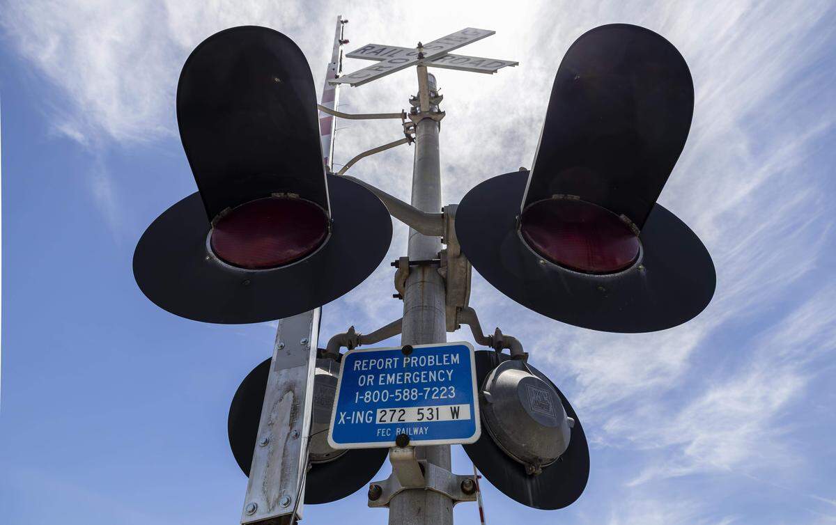 Un letrero indica el número al que llamar para reportar un problema en un cruce ferroviario cerca de North Dixie Highway y Northeast Third Street en Pompano Beach, Florida.