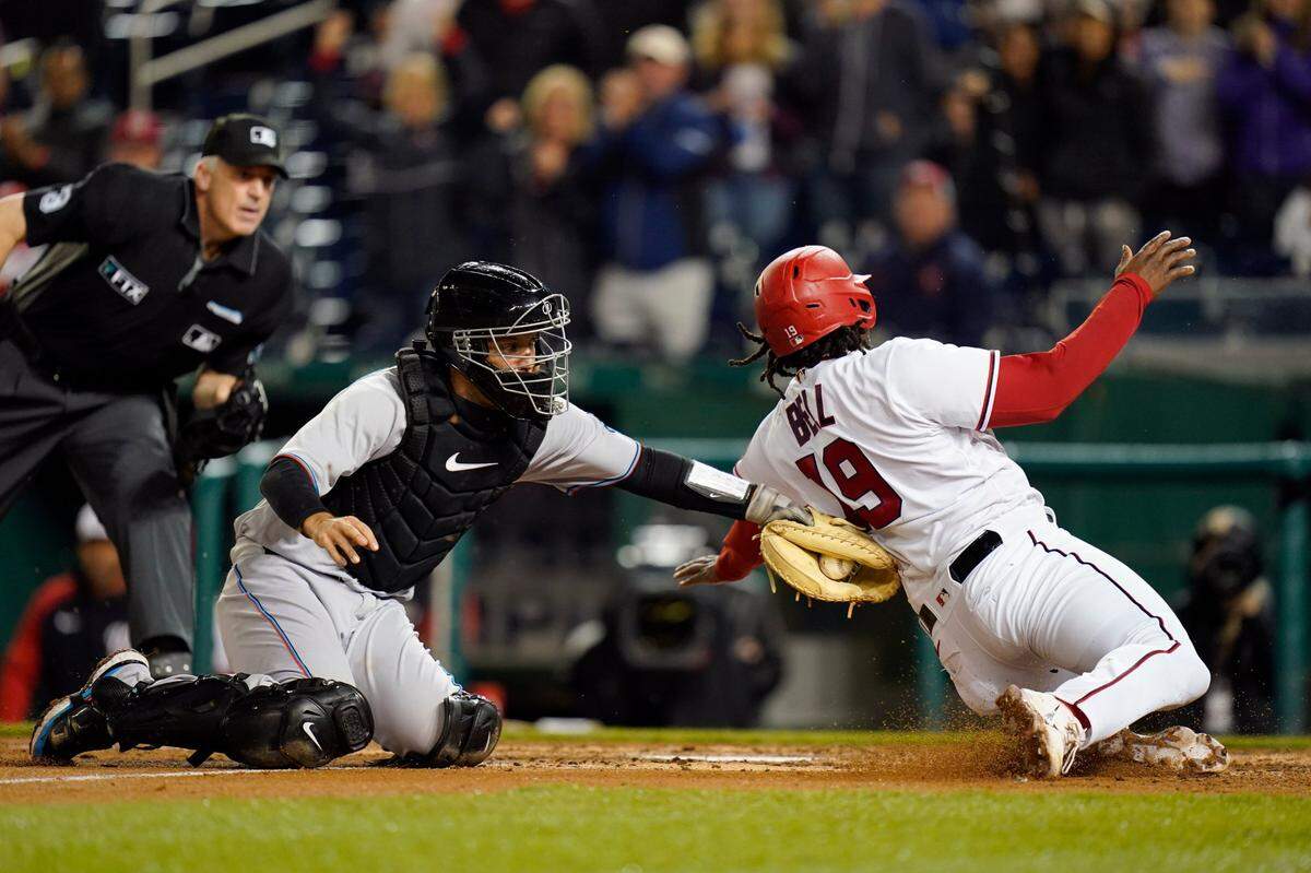 El receptor de los Marlins de Miami Jacob Stallings pone out al primera base de los Natcionales Josh Bell en una jugada en el home, en el cuarto inning del partido celebrado el 26 de abril de 2022 en Washington.