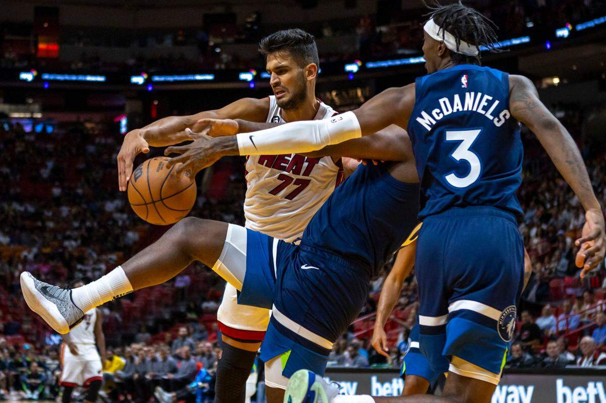 El centro del Heat Omer Yurtseve lucha por la pelota con Taurean Prince (12) y Jaden McDaniels (3), de los Timberwolves de Minnesota, en la primera mitad del partido de pretemporada, celebrado el 4 de octubre de 2022 en Miami.
