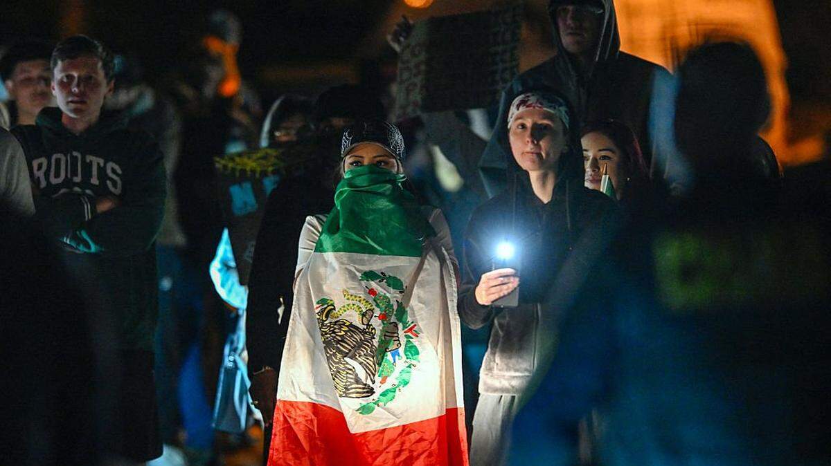 A protester covers herself with a Mexican flag while demonstrating against recent raids conducted by the US Immigration and Customs Enforcement (ICE) outside the Department of Homeland Security office in Charlotte, North Carolina, on November 16, 2025. Federal immigration officers began immigration enforcement operations in Charlotte on November 15, they confirmed in a statement. "We are surging DHS law enforcement to Charlotte to ensure Americans are safe and public safety threats are removed," Assistant Homeland Security Secretary Tricia McLaughlin said. US President Donald Trump has made deporting undocumented immigrants a key priority for his second term, after successfully campaigning against an alleged "invasion" by criminals. (Photo by Peter Zay / AFP) (Photo by PETER ZAY/AFP via Getty Images)