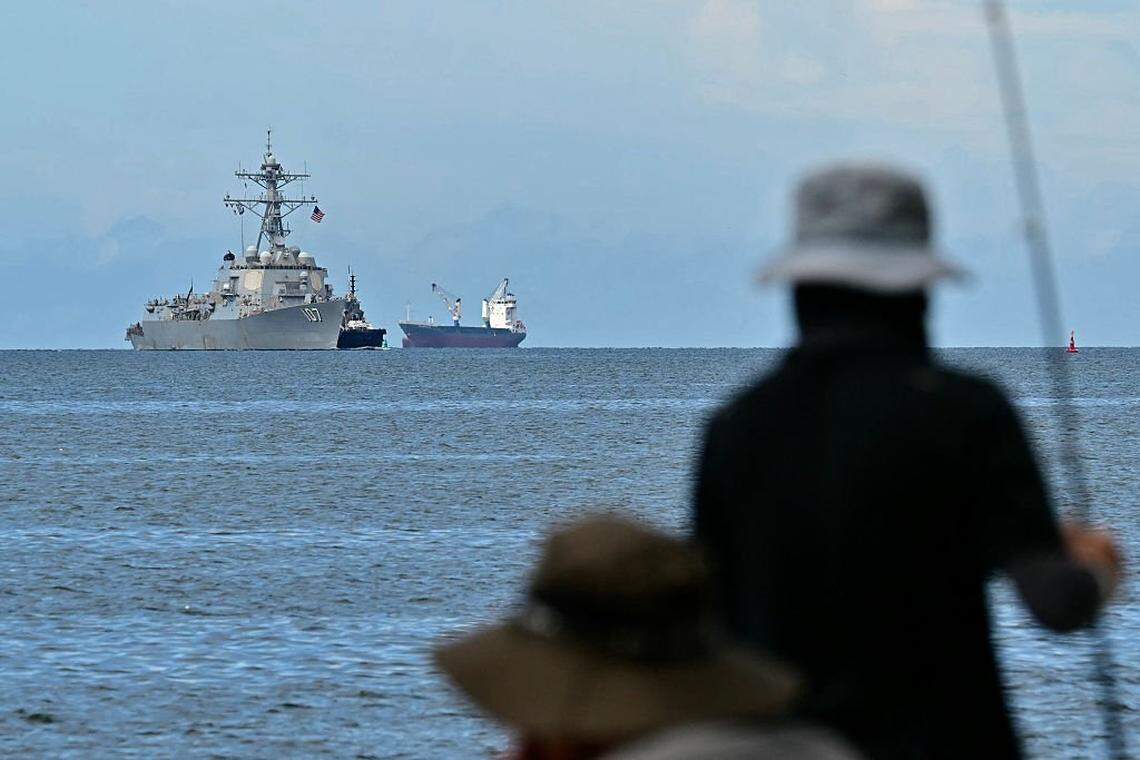 The USS Gravely warship is seen at a distance off the coast of Port of Spain on October 26, 2025, as fishermen look from the Trinidadian capital. The U.S. warship will visit Trinidad and Tobago for joint exercises near the coast of Venezuela amid Washington’s campaign against alleged drug traffickers in the region