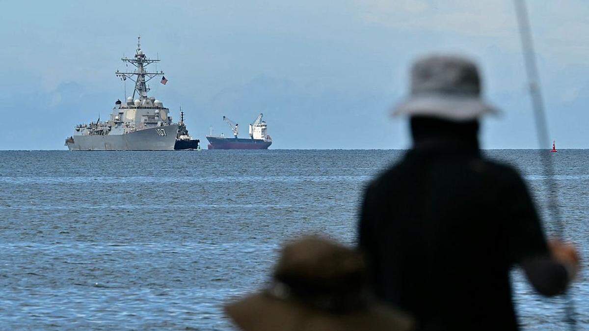 The USS Gravely warship is seen at a distance off the coast of Port of Spain on October 26, 2025, as fishermen look from the Trinidadian capital. The US warship will visit Trinidad and Tobago for joint exercises near the coast of Venezuela amid Washington's campaign against alleged drug traffickers in the region. (Photo by Martin BERNETTI / AFP) (Photo by MARTIN BERNETTI/AFP via Getty Images)