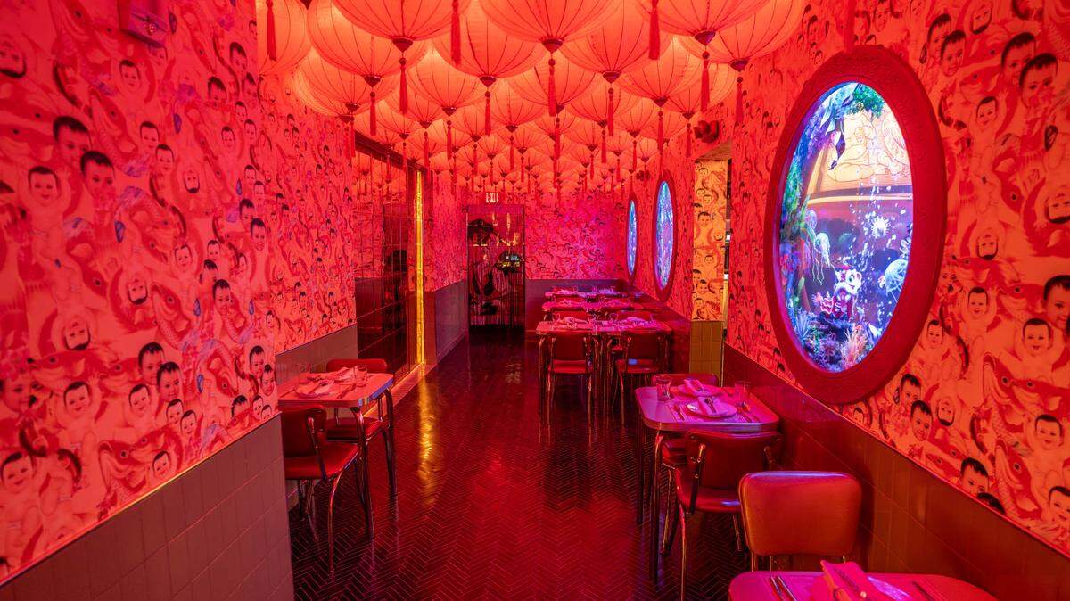 El comedor principal del restaurante cuenta con lámparas colgantes rojas y peculiares peceras.