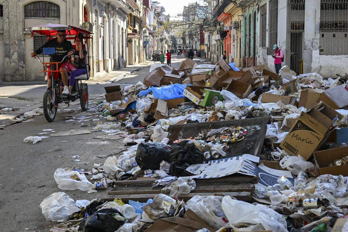 Un bicitaxi pasa junto a montones de basura en una calle de La Habana el 17 de febrero de 2026. Las condiciones de insalubridad contribuyen a la propagación de virus, que afectan más a los adultos mayores, en un momento en que el sistema de salud en Cuba está en crisis.