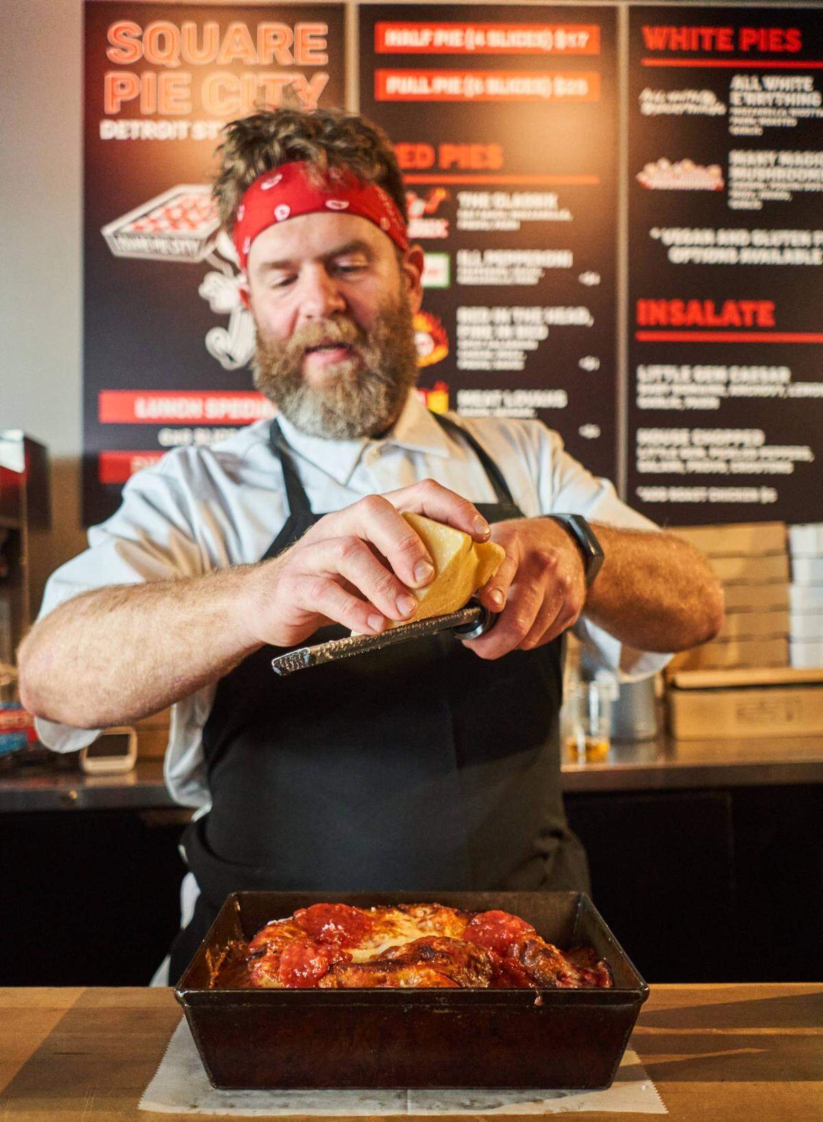 El chef Jeremiah Bullfrog ralla queso sobre una pizza en el original Square Pie City en el Design District. Presentará P.I.G. 11 —Pizza is Good, un festival gastronómico— en Freehold Studios en Wynwood.