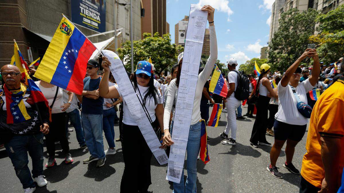 Venezolanos muestran copias de actas de votación para denunciar el presunto fraude electoral cometido por el gobierno de Nicolás Maduro, durante una protesta en Caracas el 17 de agosto de 2024.