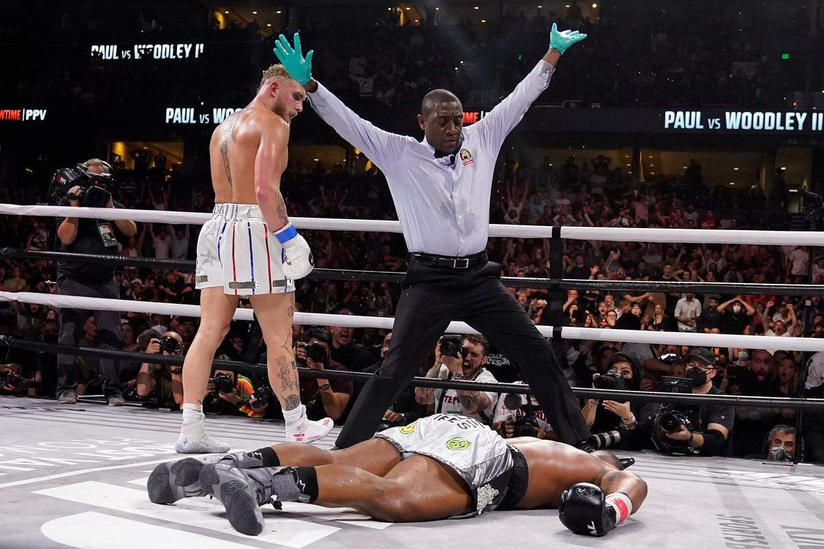 Jake Paul (izq.) mira a Tyron Woodley tras noquearlo en el sexto asalto en la pelea celebrada el sábado 18 de diciembre de 2021 en Tampa.