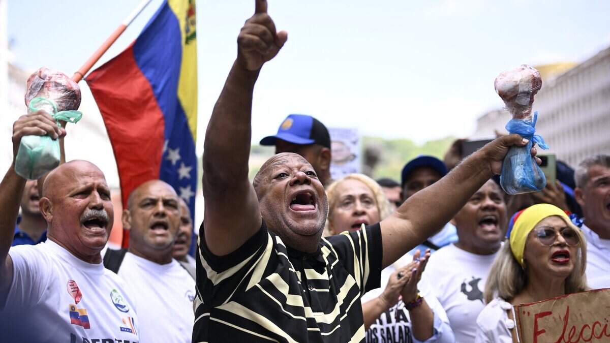 Trabajadores sindicales gritan consignas mientras sostienen huesos de res durante una protesta en la que exigen mejores condiciones laborales y elecciones presidenciales, frente al Consejo Nacional Electoral (CNE) en Caracas, el 9 de junio de 2026.