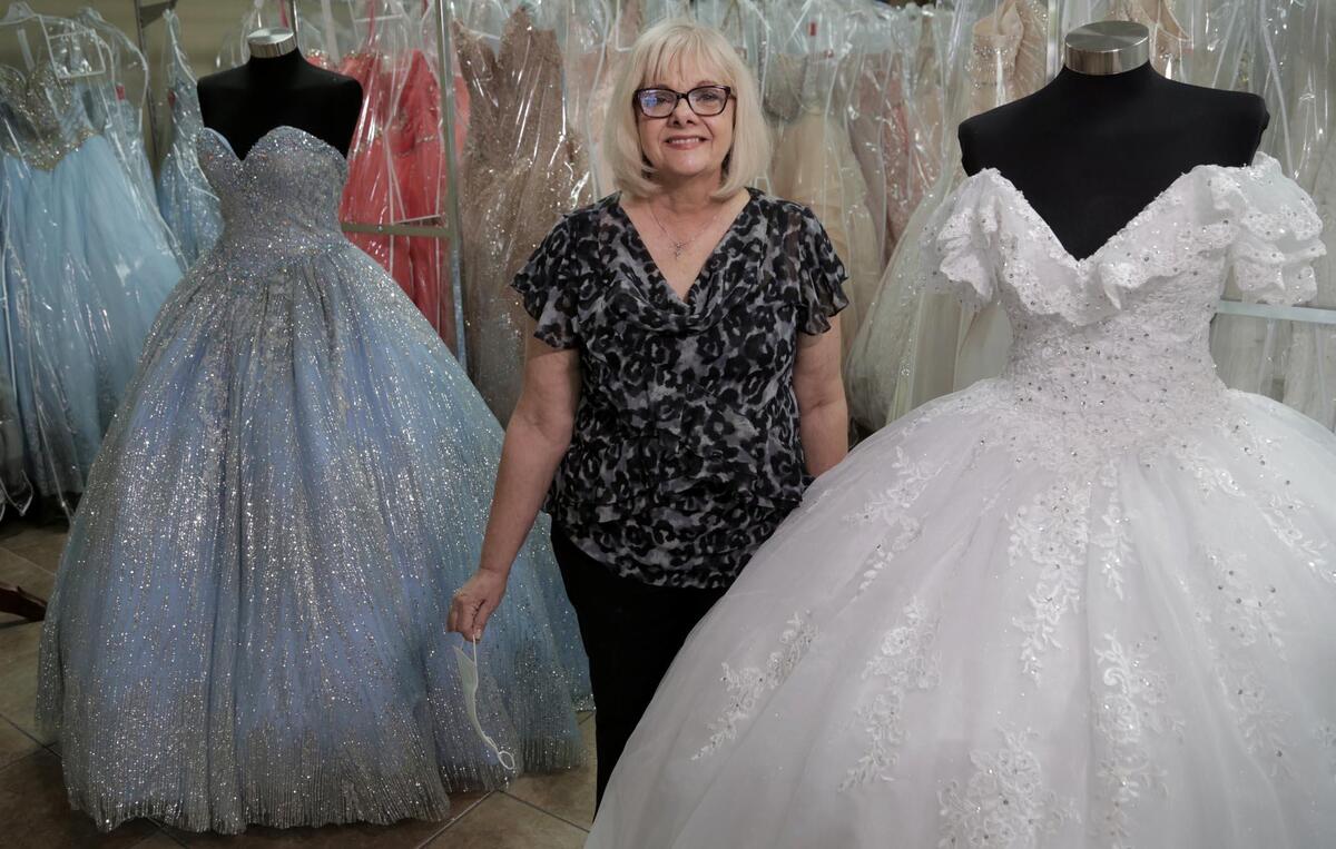 Lilian Llanos Zayas entre algunos de los vestidos de fiesta que se alquilan en su tienda, Zayas Bridal & Quinceañeras, en Hialeah.