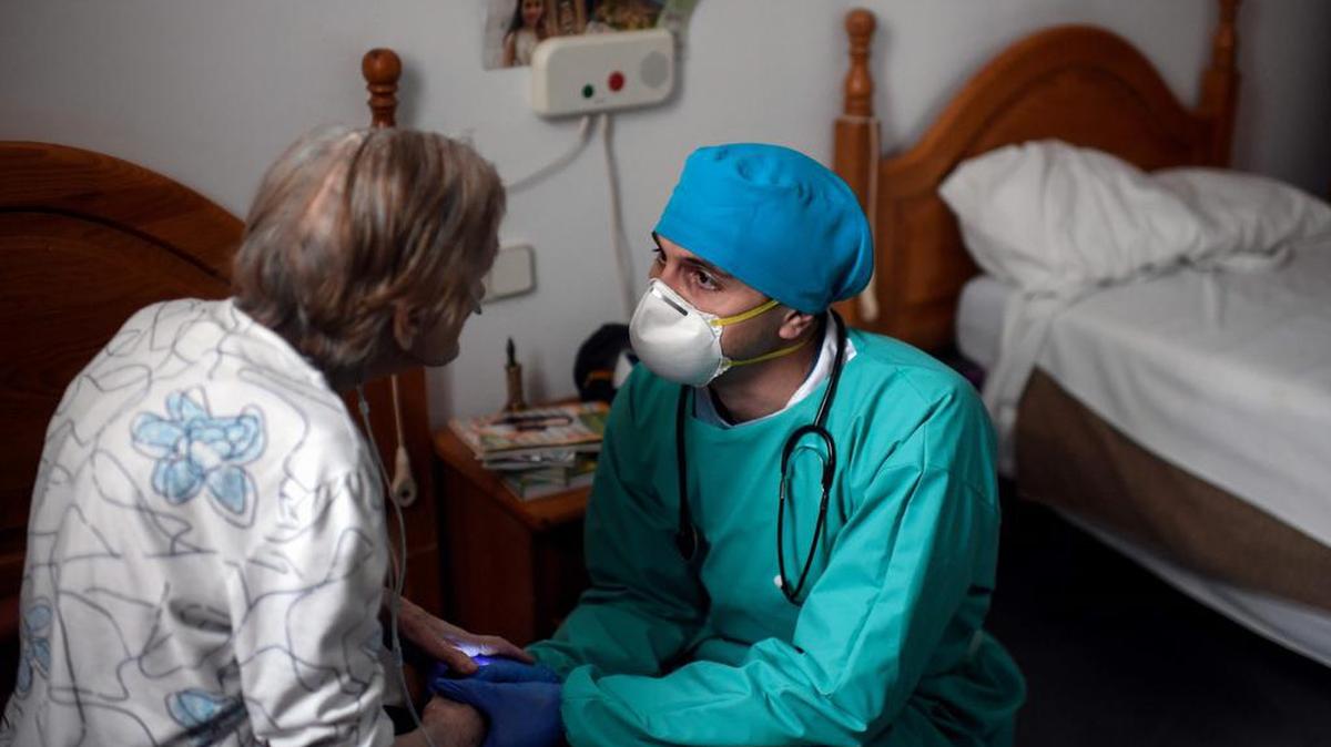 El médico venezolano Diego Padrón toma las manos de un residente aislado en un hogar de ancianos para ancianos en Madrid el 24 de abril de 2020.