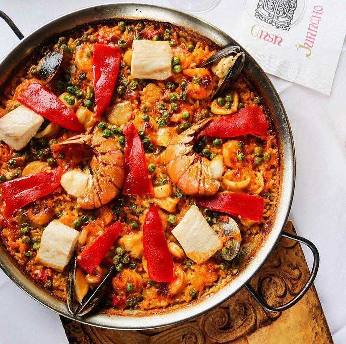 Las raciones de jamón serrano y las croquetas son generosas, pero los comensales deben dejar espacio para la galardonada paella de mariscos de Casa Juancho.