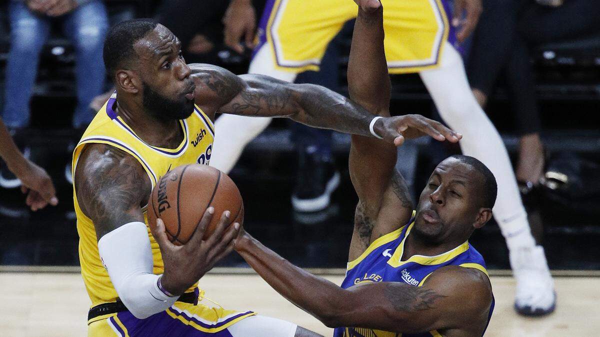 La estrella de los Lakers LeBron James (izq.) recibe la falta de Andre Iguodala, de los Warriors, en un partido de pretemporada el 10 de octubre de 2018 en Las Vegas.