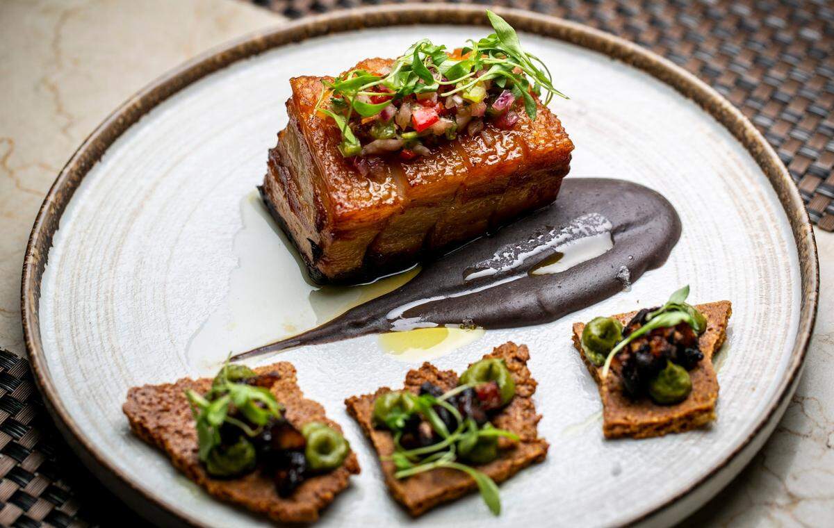 Panza de cerdo ahumado y confitado con pasta de frijoles negros, chimichurri de plátano y mousse de aguacate.