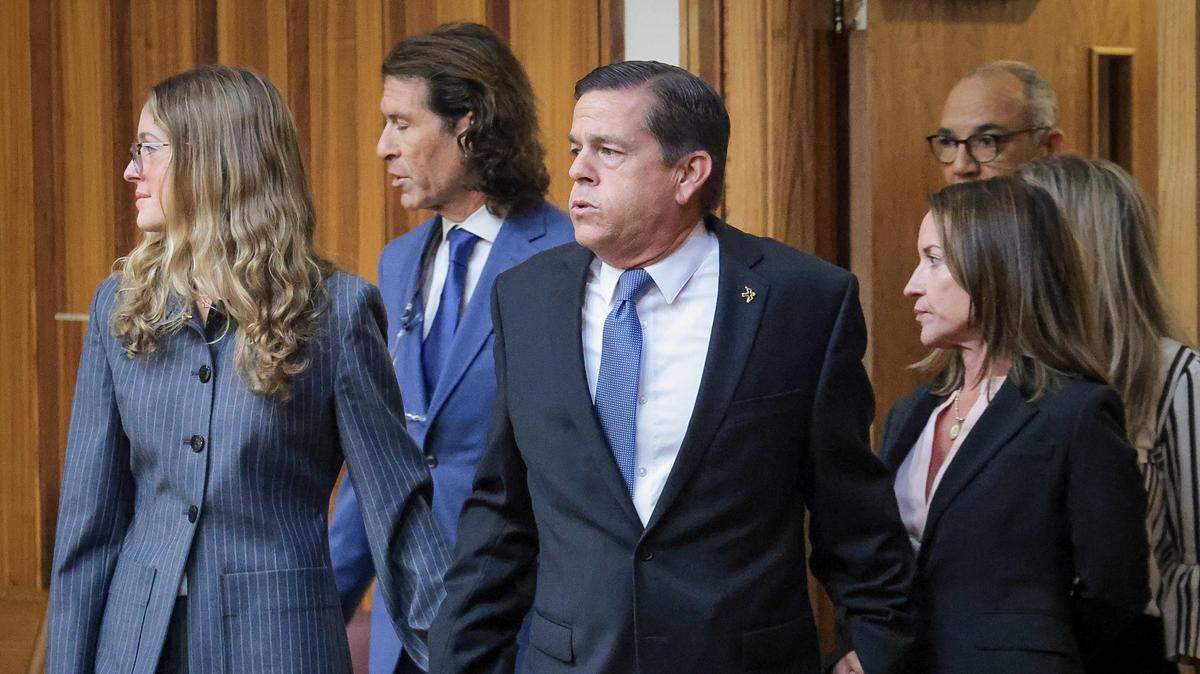 El agente de bienes raíces George Pino, en el centro, ingresa a la corte sosteniendo las manos de su hija, Carolina Pino, izquierda, y su esposa, Cecilia Pino, derecha, mientras su abogado, familiares y partidarios se reunieron en la Sala 4-1 en el Edificio de Justicia Richard E. Gerstein el 21 de noviembre de 2024 en Miami.