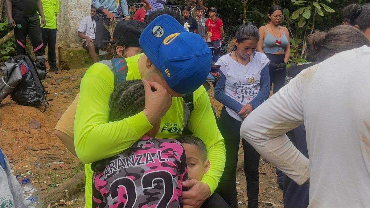 Migrantes se abrazan y oran al llegar a la frontera entre Colombia y Panamá.
