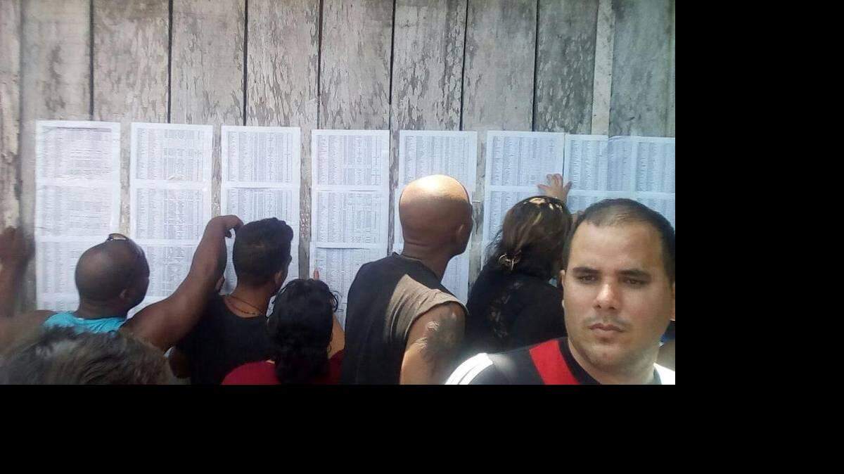Migrantes cubanos en Turbo, Colombia, buscan sus nombres en una lista. 