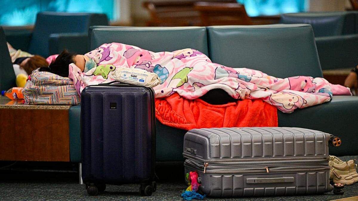 Travellers sleep on chairs as flights are cancelled at Orlando International Airport in Orlando, Florida on October 30, 2025. Flights at Orlando International Airport faced major delays on October 30, after the Federal Aviation Administration (FAA) said the airport had no certified air-traffic controllers in its tower, forcing arrivals to be halted or severely delayed amid the ongoing US government shutdown. Air traffic controllers -- seen as "essential" public servants -- are kept at work during government shutdowns, but higher numbers are calling in sick rather than toiling without pay, leading to shortages. (Photo by Miguel J. Rodriguez Carrillo / AFP) (Photo by MIGUEL J. RODRIGUEZ CARRILLO/AFP via Getty Images)