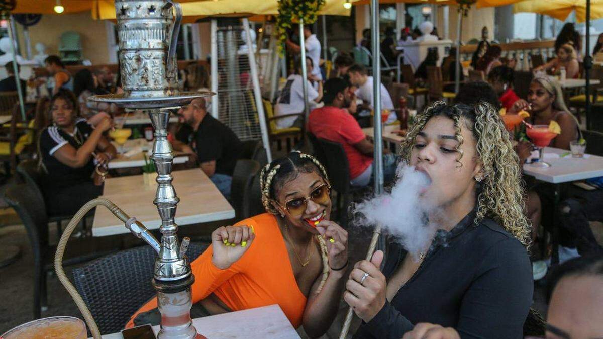 Las vacacionistas Karsyn Mcleod, y Zayasha Fowler, ambas de 21 años, sentadas en un hookah bar and lounge en Ocean Drive en South Beach el 22 de marzo de 2021.