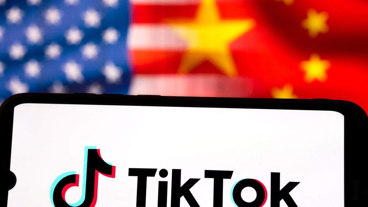 El logotipo de TikTok aparece en la pantalla de un teléfono inteligente, con las banderas de Estados Unidos y China mostradas en la pantalla de una computadora al fondo, en esta ilustración tomada en Atenas, Grecia, el 19 de septiembre de 2025.