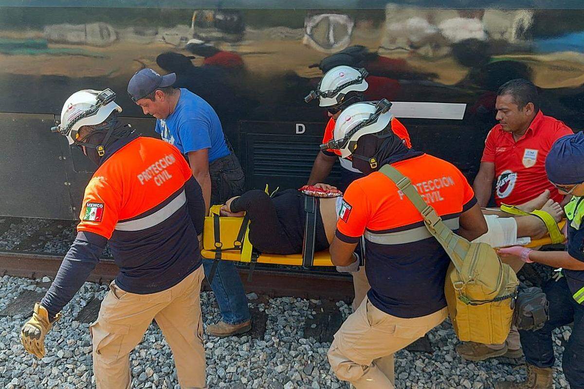 Civil Protection members rescue a woman from the Interoceanic train that derailed in Nizanda, Oaxaca state, on the route to Coatzacoalcos, Mexico, on December 28, 2025. At least 20 people were injured on December 28, 2025, after a train crashed in the southern Mexican state of Oaxaca, authorities said. (Photo by Rusvel RASGADO / AFP via Getty Images)